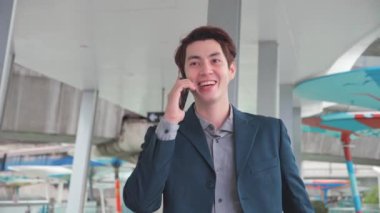 Genç Asyalı işadamı işe giderken telefonla konuşuyor.