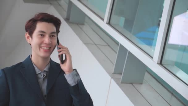 若いアジアのビジネスマンが仕事に向かう途中で電話をかける — ストック動画