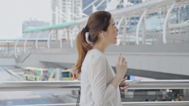 Şehir binasının dışında Asyalı iş kadını telefonda konuşuyor. 4K Slow Motion şirket çekimi