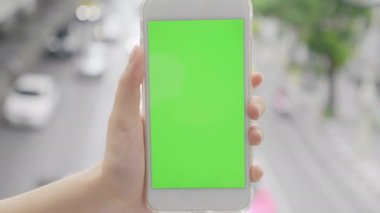 El ele tutuşan akıllı telefon yeşil ekran krom anahtar trafik şehri bulanık arkaplan