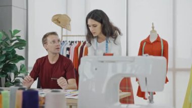 İki yaratıcı moda tasarımcısı modern stüdyoda tasarım projesini tartışıyor.