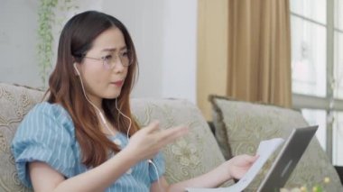 Ciddi Asyalı uzak mesafe öğrencisi bilgisayar eğitimi konseptini öğrenmek için bilgisayar konferansında videoyla iletişim kurarak kulaklık kullanıyor. Evde çevrimiçi çalışma mesafesi