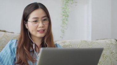 Ciddi Asyalı uzak mesafe öğrencisi bilgisayar eğitimi konseptini öğrenmek için bilgisayar konferansında videoyla iletişim kurarak kulaklık kullanıyor. Evde çevrimiçi çalışma mesafesi
