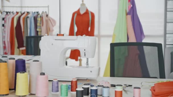 スタジオでミシンと半完成した衣類 大きなテーラーズデスクと服のデザインスタジオ マネキン 壁に固定された多数のスケッチ — ストック動画