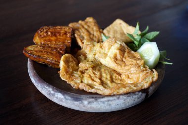 Yumurta, tempeh ve patlıcan penisi Endonezya mutfağında ahşap bir masada.                                     
