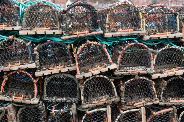 Yengeç tuzakları üst üste yığılmış, halatla bağlanmış, bir balıkçı teknesine yüklenmeye hazırlanıyorlar..