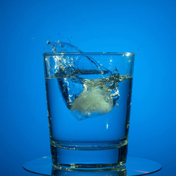 Splashes in a glass of water on a colored background