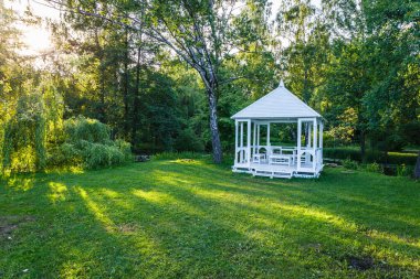 Wooden arbor in the public park and a meadow grass field.