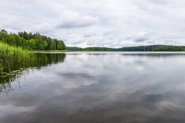 Bulutlu gökyüzüne karşı gölün manzarası.