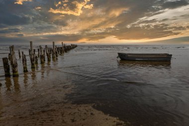 Old abandoned wooden pier or jetty remains and fishermens boat.
