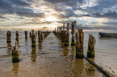 Old abandoned wooden pier or jetty remains and fishermens boat.