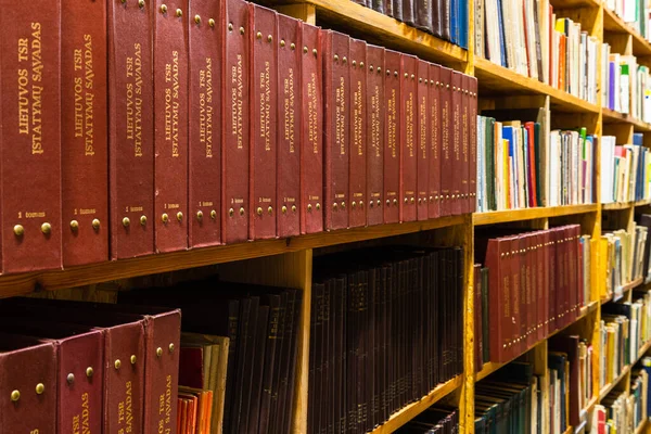 Old vintage books on a wooden shelf in the library.