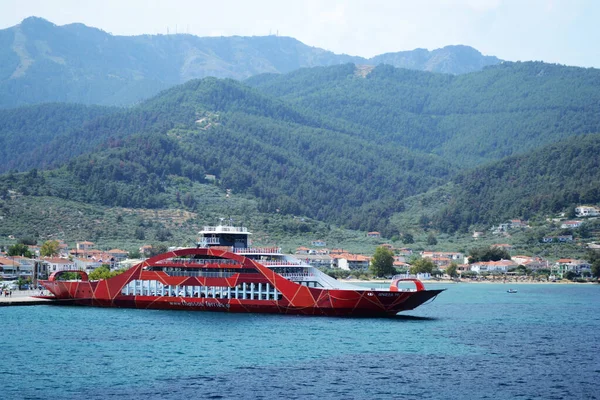 THASSOS, GREECE - 21 AĞUSTOS 2017: Limanda kırmızı feribot ve arkasında dağlar olan Thassos 'tan manzara