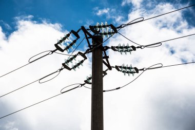 Mavi gökyüzünde yalıtımlı, kabarık bulutlu elektrik direği..