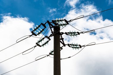 Mavi gökyüzünde yalıtımlı, kabarık bulutlu elektrik direği..