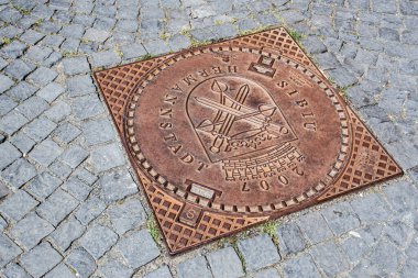 SIBIU, ROMANIA - 28 HAZİRAN 2021: Asfalt bir yolun ortasında kanalizasyon kapağı.