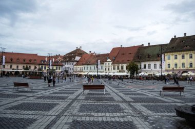 SIBIU, ROMANIA - 19 AĞUSTOS 2020: Güvercinler ve turistlerle dolu Sibiu 'nun büyük meydanı. Gezinti alanı.