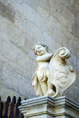 ALBA IULIA, ROMANIA - 21 AĞUSTOS 2020: kalkanlı küçük bir çocuğun heykeli. Saint Michael Katedrali 'nin ön yüzü. Alba Carolina Kalesi.