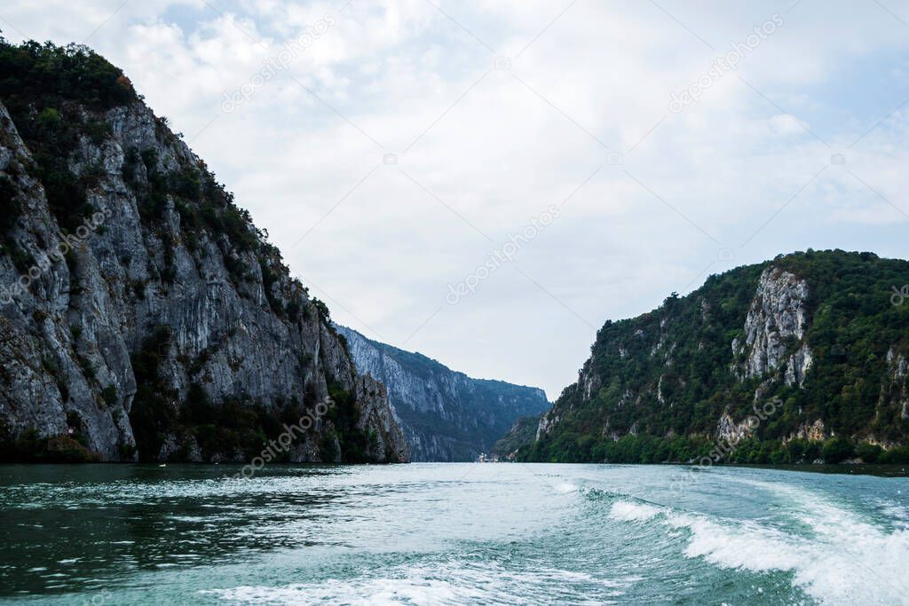 The water foam in the back of a boat, mountains, Mraconia monastery and the Danube river, Cazanele Dunarii, Romania.