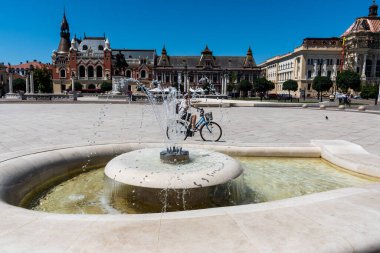 ORADEA, ROMANIA - 30 Temmuz 2021: Yunan Sarayı ile Birlik Meydanı - Katolik Piskoposluğu, Ferdinand 1 ve belediye binasının heykeli.