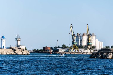 MANGALYA, ROMANIA - 31 Ağustos 2021: Mangalia limanındaki Genoves deniz feneri ve endüstriyel vinç ve silolar.
