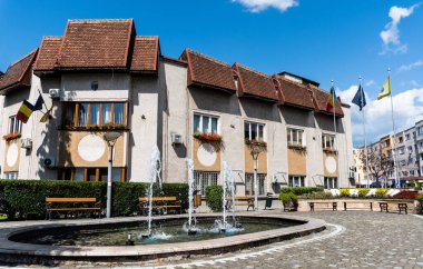 BRAD, HUNEDOARA, ROMANIA - Eylül 05, 2021: Brad Belediye Binası ve binanın yanındaki artezyen çeşmesi.