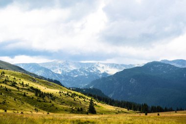 Dağlar, yeşil tepeler ve bulutlu gökyüzü, Transalpina yolu, Romanya.