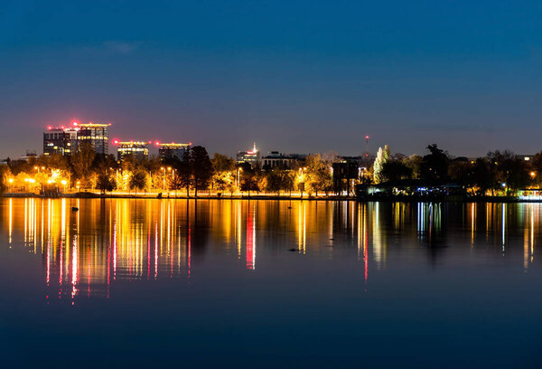 Night view of the colorful reflection of city lights in the lake's water from the Herastrau park. Bucharest, Romania.