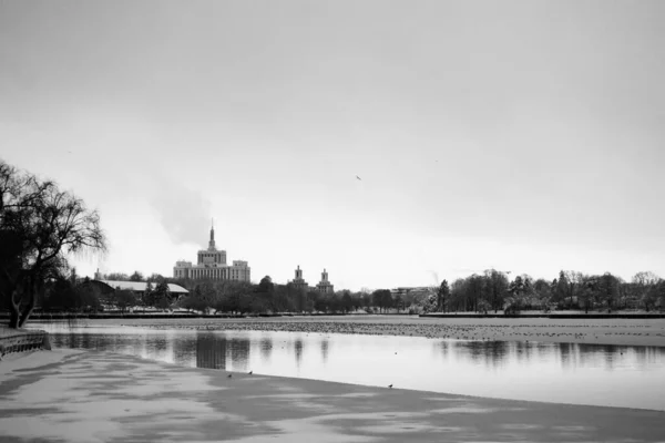 冬の街は黒と白のHerastrau公園の半分凍った湖の上に見えました — ストック写真
