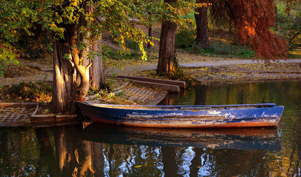 Landscape of a blue boat on the lake in the Carol park on an evening autumn at Bucharest.