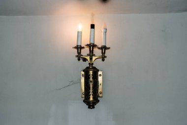 Vintage lamp without one bulb isolated on a wall.