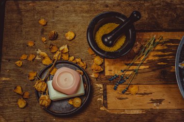 Masanın üzerine yerleştirilmiş bir fotoğraf. El yapımı sabun, kuru çiçekler, dekor. Kahverengi ahşap arka plan, boyalı cam işçiliği 