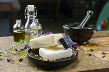 Masanın üzerine yerleştirilmiş bir fotoğraf. El yapımı sabun, kuru çiçekler, dekor. Kahverengi ahşap arka plan, boyalı cam işçiliği 