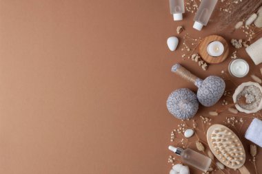 Kozmetik şişeli, mumlu ve bitkisel çantalı spa tedavisi, kahverengi arka planda havlu. Düz yat, boşluğu kopyala.