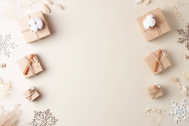 El işi kağıdında paketleme hediyeleriyle Noel süsleri ve bej arka planda çiçekler. Sıfır Noel ziyanı konsepti. Düz yat, boşluğu kopyala