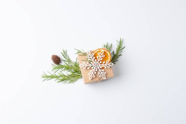 Beyaz arka planda biberiyeli el sanatları kağıdında çevre dostu hediyeyle Noel kompozisyonu. Sıfır Noel ziyanı konsepti. Düz yat, boşluğu kopyala