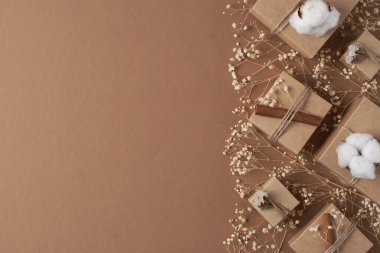 Hediyeli Noel süsleri ve kahverengi arka planda çiçekler. Düz yat, boşluğu kopyala