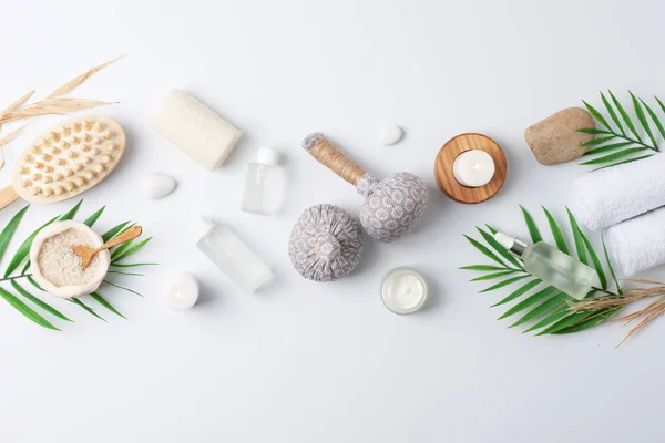 Spa treatment with natural skin care products, herbal bags, towel and wash on white background. Flat lay, copy space.