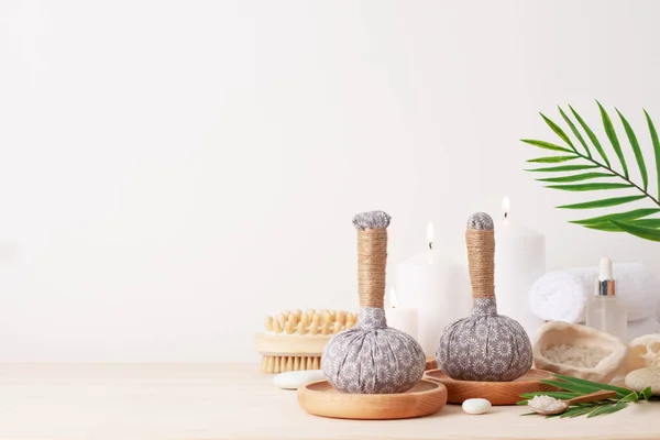 Spa treatment with herbal bags and candle on white background. Close up, copy space.