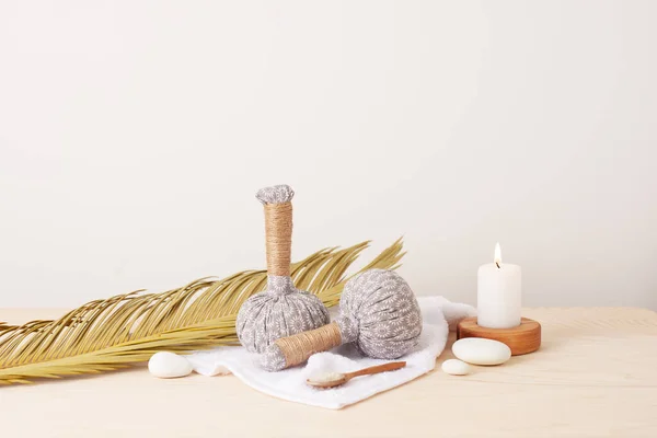 Spa treatment with herbal bags and candle on white background. Close up, copy space.