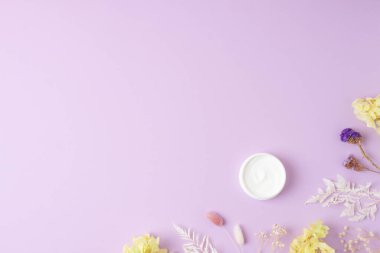 Gül arka planında çiçekler olan kozmetik kremi kavanozu. Düz yat, boşluğu kopyala