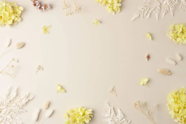 Cosmetic background with flowers on pastel beige. Flat lay, copy space