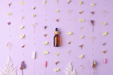 Gül arka planında çiçekler olan kozmetik şişesi. Düz yatıyordu