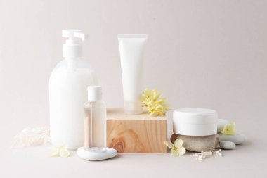 Ahşap kürsü ve çiçekli kozmetik cilt bakım ürünleri, gri arka planda taş. Kapat, boşluğu kopyala