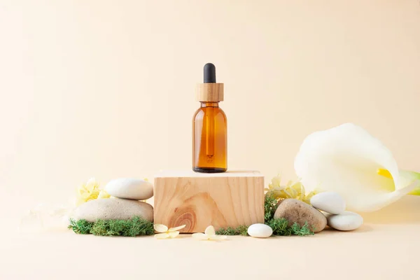 Cosmetic bottle with wood podium and flowers, moss, stone on pastel beige background. Close up, copy space
