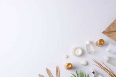 Beyaz arka planda kozmetik şişe, mum ve palmiye yaprağı ile kaplıca tedavisi. Düz yat, boşluğu kopyala