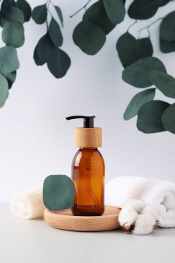 Beyaz arka planda kozmetik şişe, havlu ve okaliptüs ile kaplıca tedavisi. Kapat, boşluğu kopyala
