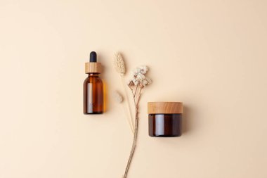 Makyaj bej arka planda kozmetik cilt bakım ürünleri ve çiçeklerle minimum bileşim. Düz yatıyordu.