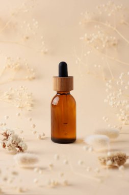 Pastel bej arka planda çiçekli kozmetik şişesi. Kapat.