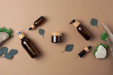 Kahverengi arka planda okaliptüs ve odun içeren kozmetik cilt bakım ürünleri. Düz yat, boşluğu kopyala